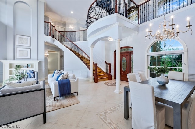 dining room featuring a chandelier, decorative columns, light tile floors, and a high ceiling