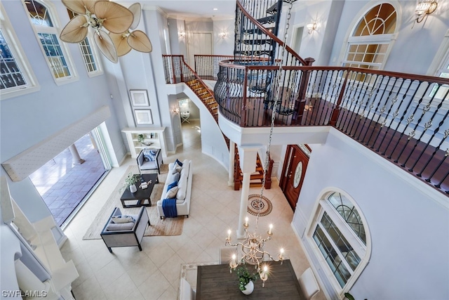 tiled living room with a high ceiling and ceiling fan with notable chandelier