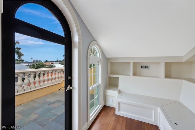 entryway with built in features, wood-type flooring, and vaulted ceiling