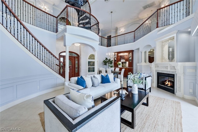 living room with a notable chandelier, decorative columns, a high ceiling, and light tile flooring