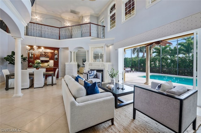 tiled living room with plenty of natural light, an inviting chandelier, a towering ceiling, and a fireplace