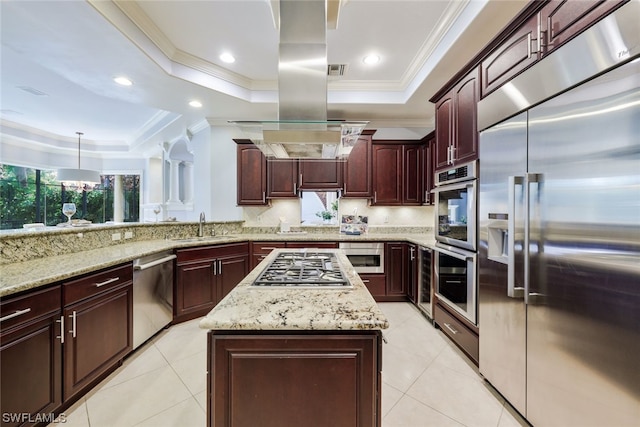 kitchen featuring built in appliances, a kitchen island, a tray ceiling, and light stone counters