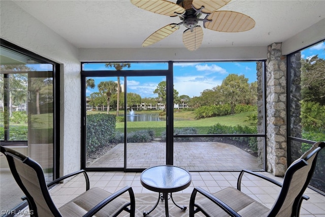 sunroom featuring ceiling fan and a water view