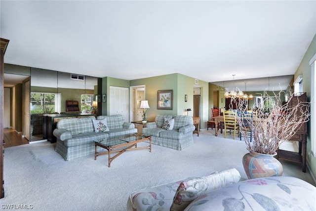 carpeted living room featuring an inviting chandelier