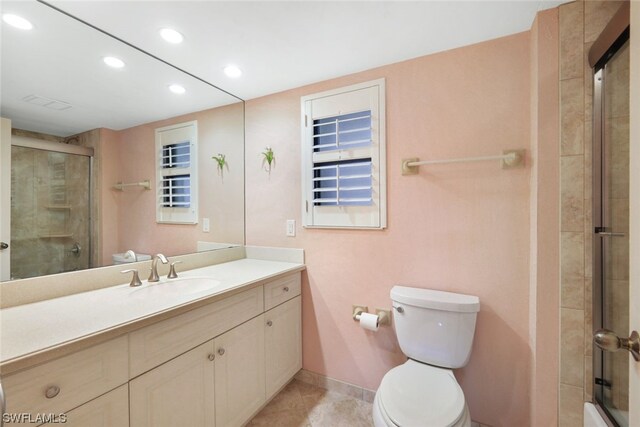 bathroom with tile patterned floors, vanity, toilet, and a shower with door