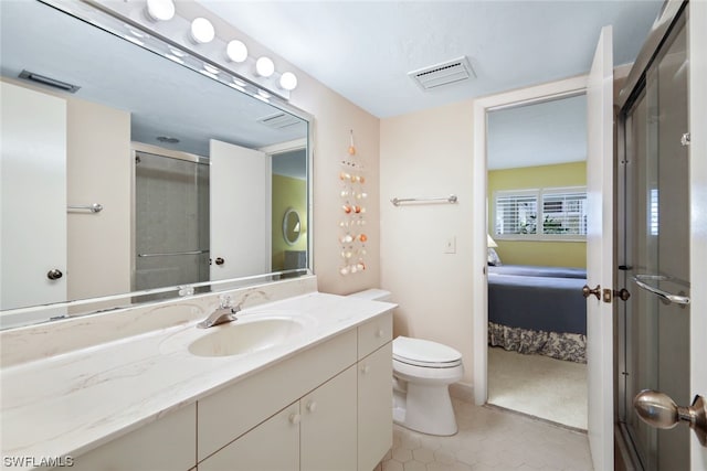 bathroom with an enclosed shower, vanity, toilet, and tile patterned floors