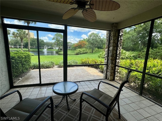 unfurnished sunroom featuring ceiling fan, a water view, and a wealth of natural light