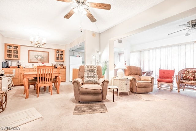 carpeted living room with a textured ceiling and ceiling fan with notable chandelier