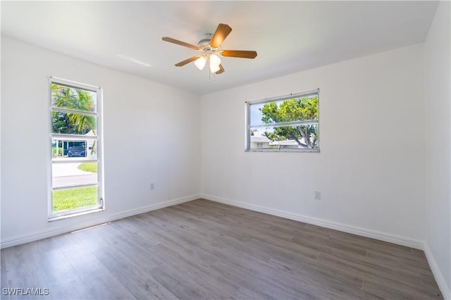 empty room featuring a wealth of natural light, dark hardwood / wood-style flooring, and ceiling fan