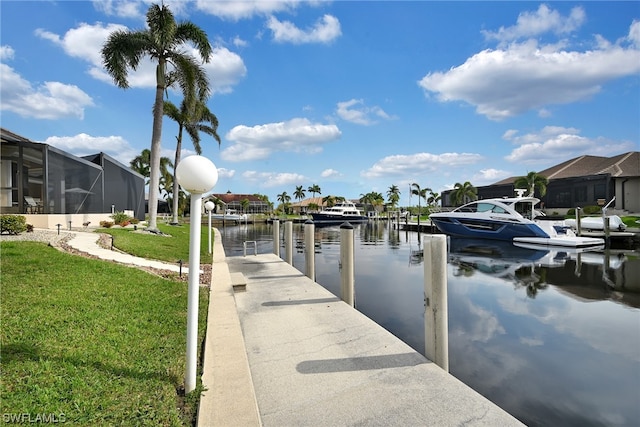 dock area with a lawn, glass enclosure, and a water view