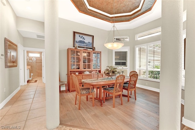 dining room with light tile floors and a raised ceiling