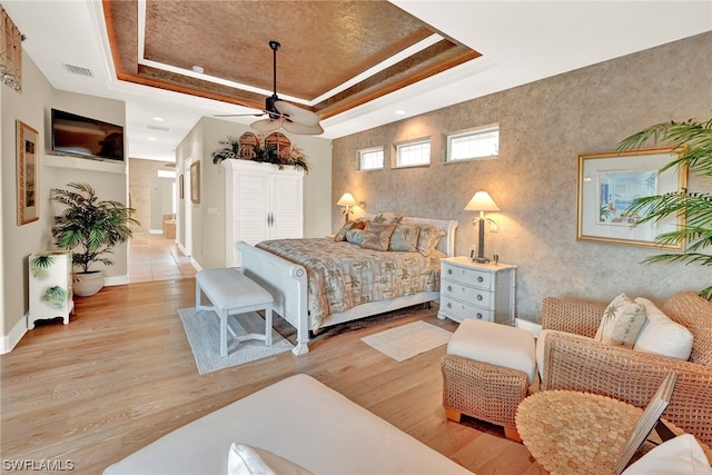 bedroom featuring a raised ceiling and light hardwood / wood-style flooring