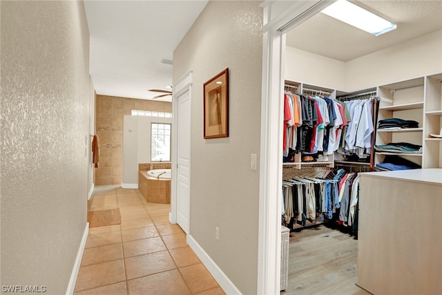 spacious closet with light tile floors and ceiling fan