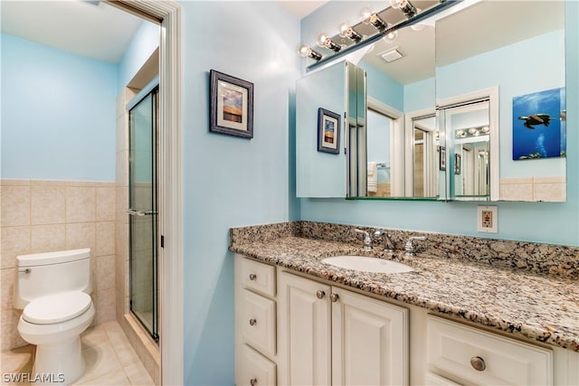 bathroom featuring tile walls, toilet, a shower with shower door, tile floors, and vanity