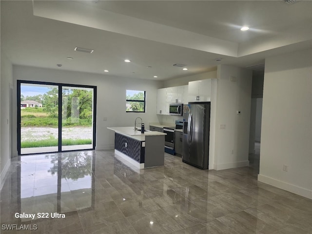 kitchen with appliances with stainless steel finishes, a center island with sink, white cabinetry, and sink