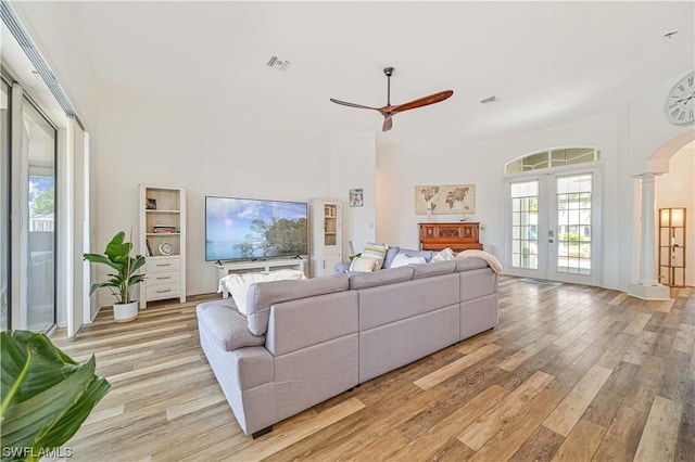 living room featuring french doors, ornate columns, light hardwood / wood-style flooring, and ceiling fan