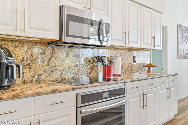 kitchen featuring backsplash, white cabinets, stainless steel appliances, and light wood-type flooring