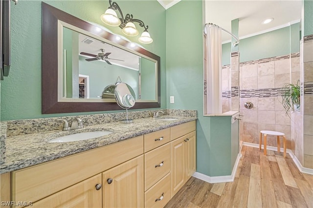 bathroom featuring ceiling fan, vanity, wood-type flooring, and a tile shower