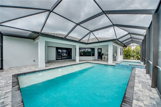 view of pool featuring a patio area, an in ground hot tub, pool water feature, and glass enclosure