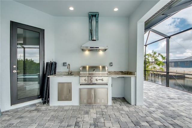 view of terrace with an outdoor kitchen, area for grilling, glass enclosure, and sink