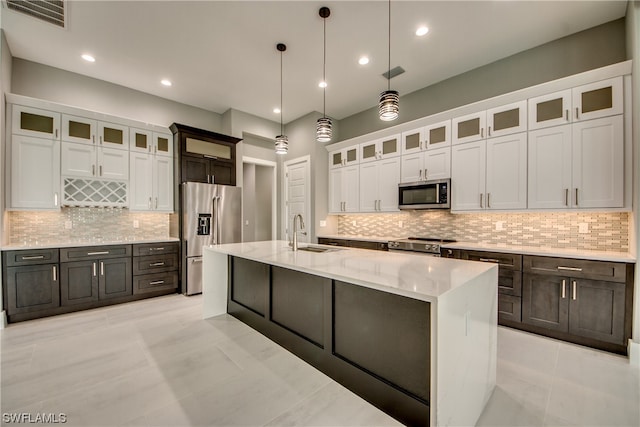 kitchen featuring light tile floors, hanging light fixtures, white cabinets, stainless steel appliances, and tasteful backsplash