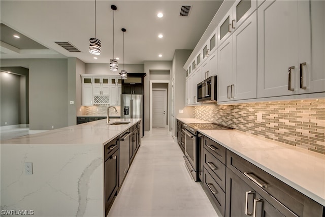 kitchen with white cabinetry, backsplash, sink, stainless steel appliances, and pendant lighting