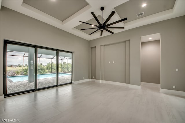 tiled spare room featuring coffered ceiling, a raised ceiling, and ceiling fan