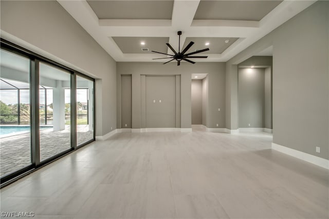 empty room with coffered ceiling, plenty of natural light, ceiling fan, and elevator