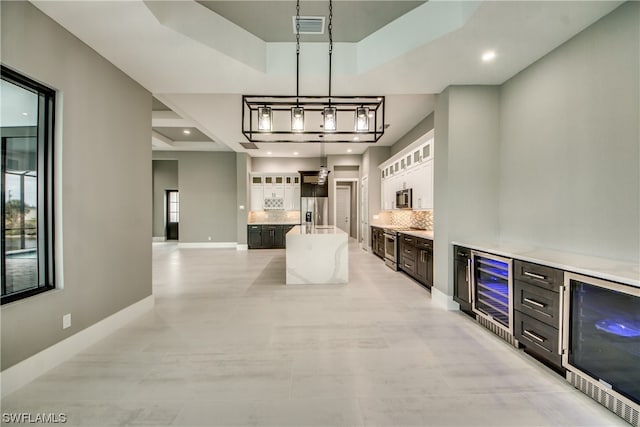 tiled dining space with a tray ceiling, beverage cooler, and bar