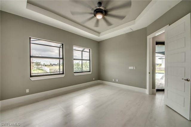 spare room with a raised ceiling and ceiling fan