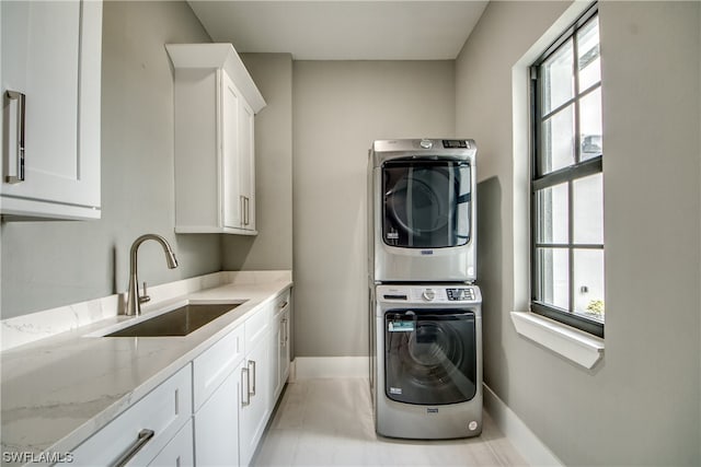 laundry area with cabinets, a healthy amount of sunlight, sink, and stacked washer and dryer