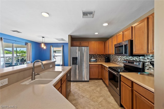 kitchen with decorative backsplash, appliances with stainless steel finishes, sink, light tile patterned floors, and pendant lighting