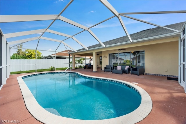 view of swimming pool featuring an outdoor living space, glass enclosure, ceiling fan, and a patio area