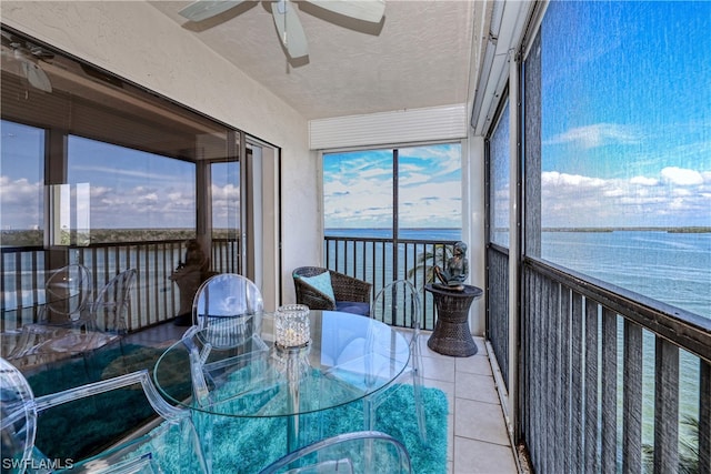 unfurnished sunroom with a water view, ceiling fan, and a wealth of natural light