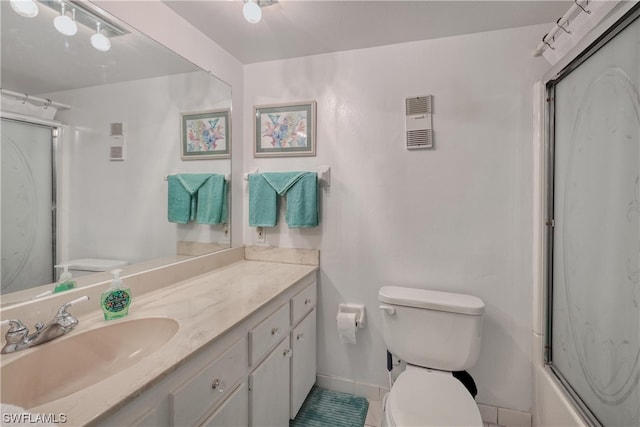 full bathroom with toilet, tile flooring, vanity, and bath / shower combo with glass door