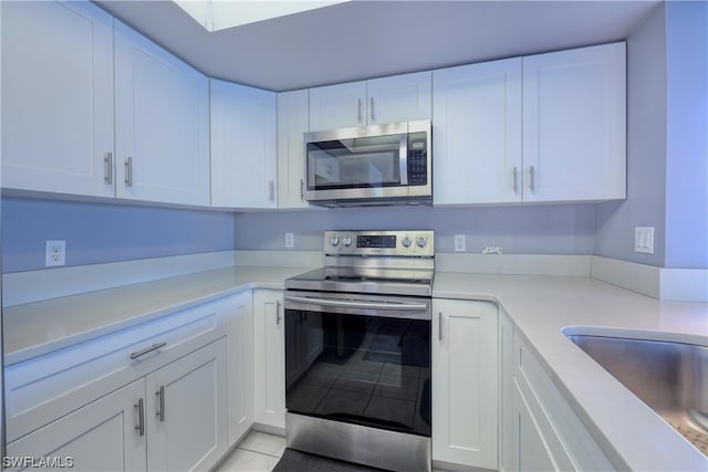 kitchen with white cabinets, appliances with stainless steel finishes, and light tile floors