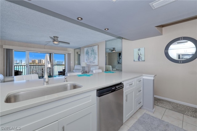 kitchen with stainless steel dishwasher, light tile flooring, ceiling fan, white cabinetry, and sink