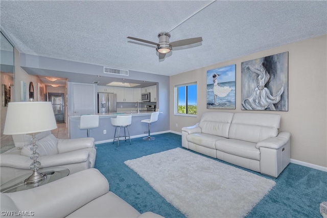 living room featuring light carpet, a textured ceiling, and ceiling fan