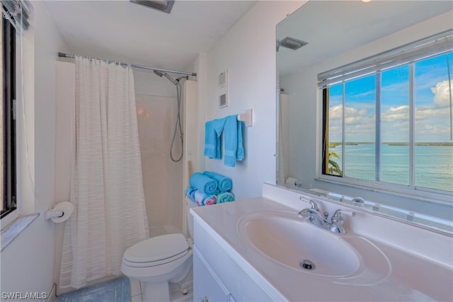 bathroom with a water view, toilet, vanity with extensive cabinet space, and a wealth of natural light