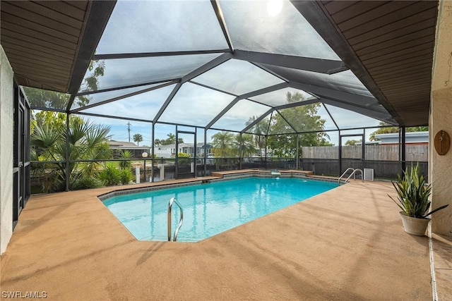 view of pool with glass enclosure and a patio area