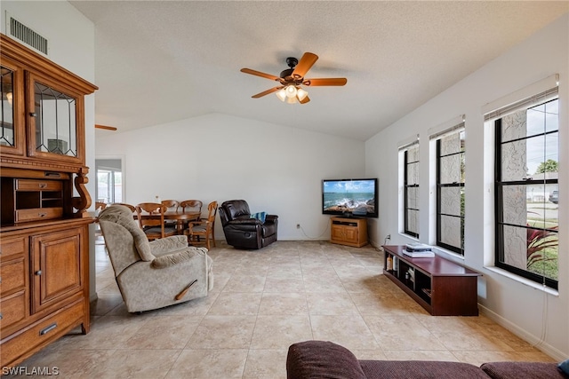 tiled living room featuring a textured ceiling, ceiling fan, and vaulted ceiling