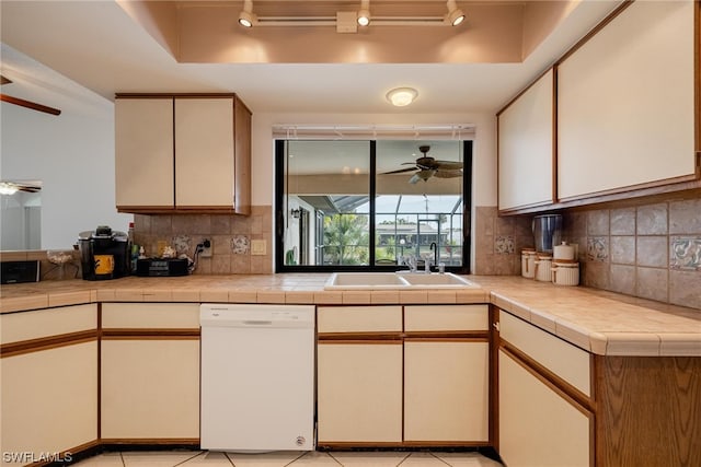 kitchen featuring white dishwasher, a raised ceiling, sink, and tile countertops