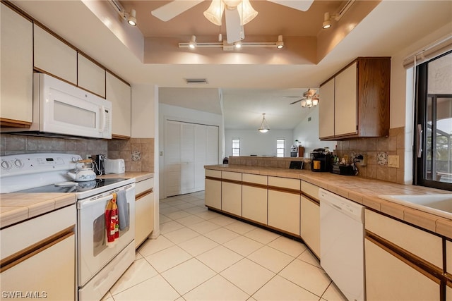 kitchen with a raised ceiling, tile countertops, decorative backsplash, and white appliances