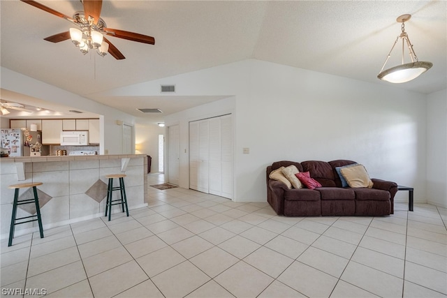 tiled living room featuring ceiling fan and vaulted ceiling