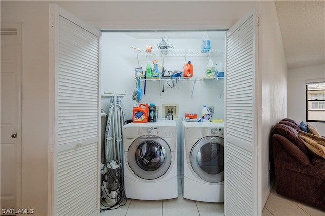 clothes washing area with washing machine and dryer and light tile patterned floors