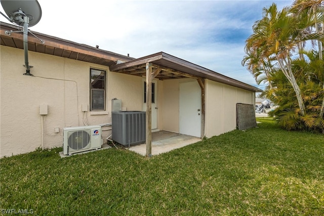 rear view of property with ac unit, a patio area, a yard, and central AC