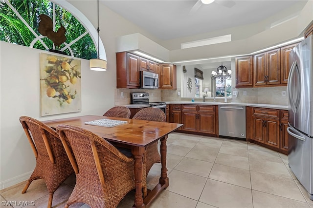 kitchen with light tile patterned floors, decorative light fixtures, backsplash, and appliances with stainless steel finishes