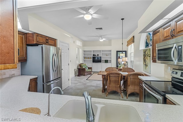 kitchen featuring sink, decorative light fixtures, kitchen peninsula, stainless steel appliances, and backsplash