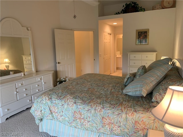 carpeted bedroom featuring a towering ceiling, a closet, and ensuite bathroom