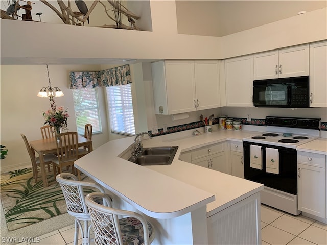 kitchen featuring white electric stove, a breakfast bar area, a notable chandelier, sink, and light tile floors